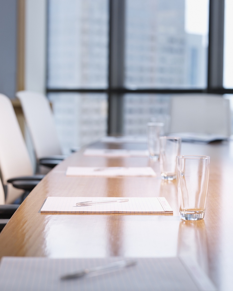 Empty boardroom table with notepads and glasses on it